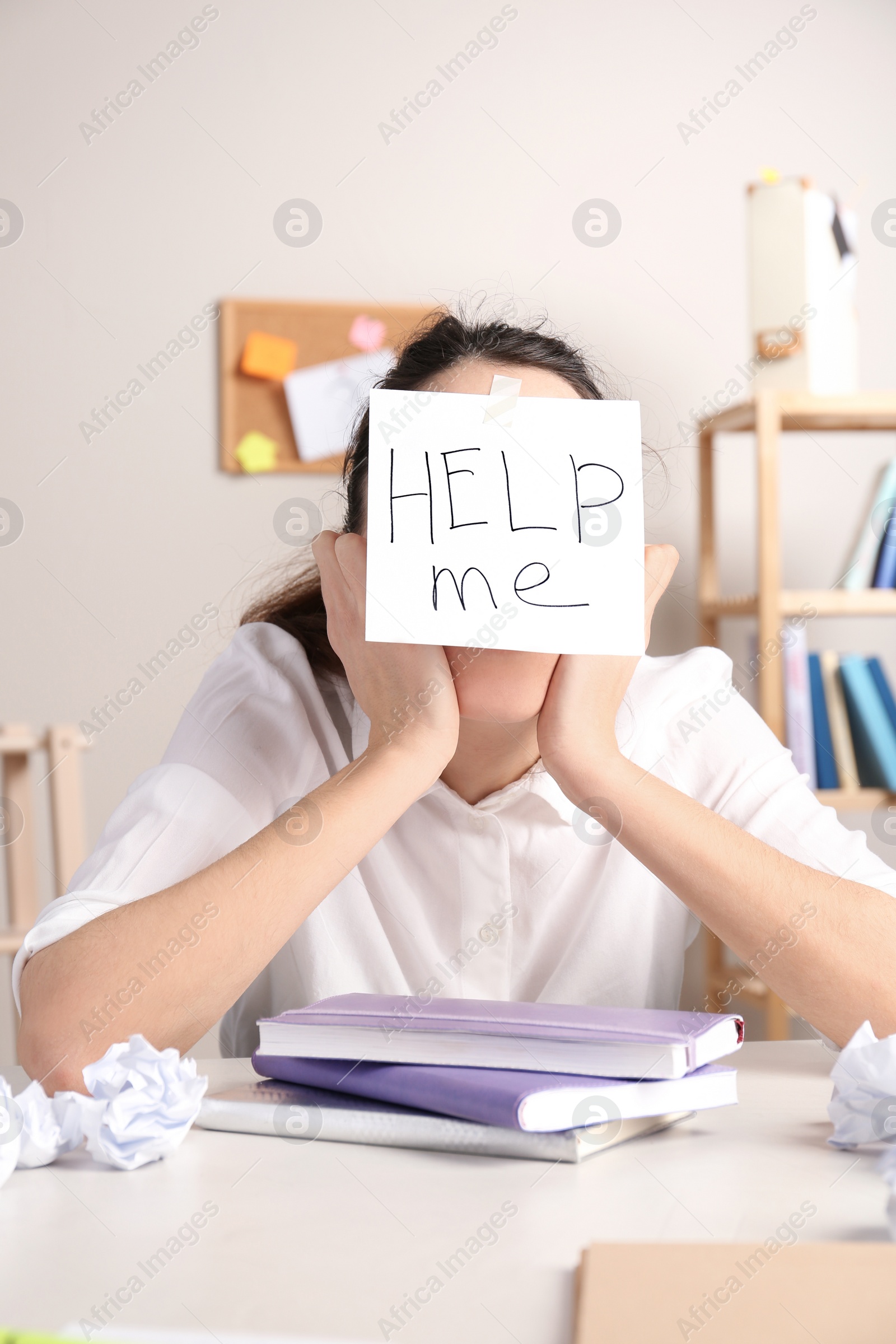 Photo of Young woman with note HELP ME on forehead at workplace