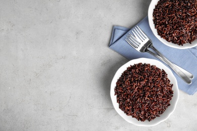 Photo of Flat lay composition with delicious cooked brown rice on grey table. Space for text