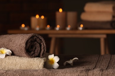 Spa composition with towels and plumeria flowers on massage table in wellness center