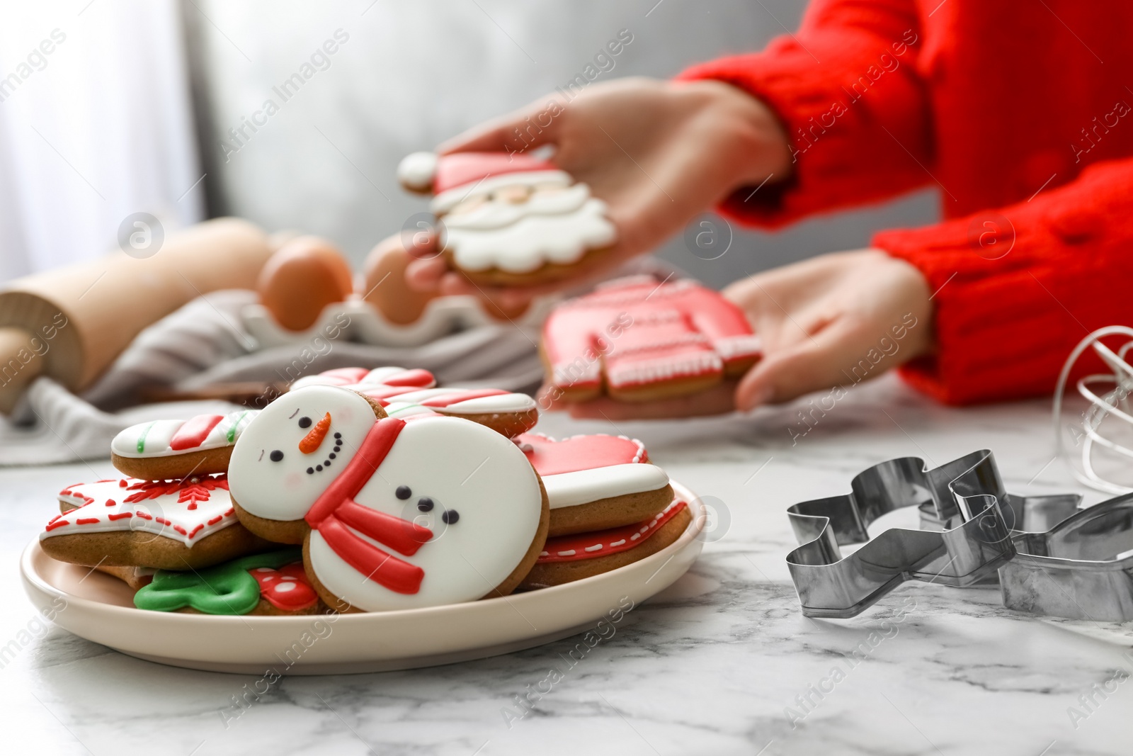 Photo of Woman holding delicious homemade Christmas cookies at white marble table, focus on plate