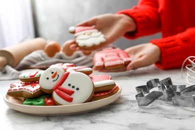 Woman holding delicious homemade Christmas cookies at white marble table, focus on plate