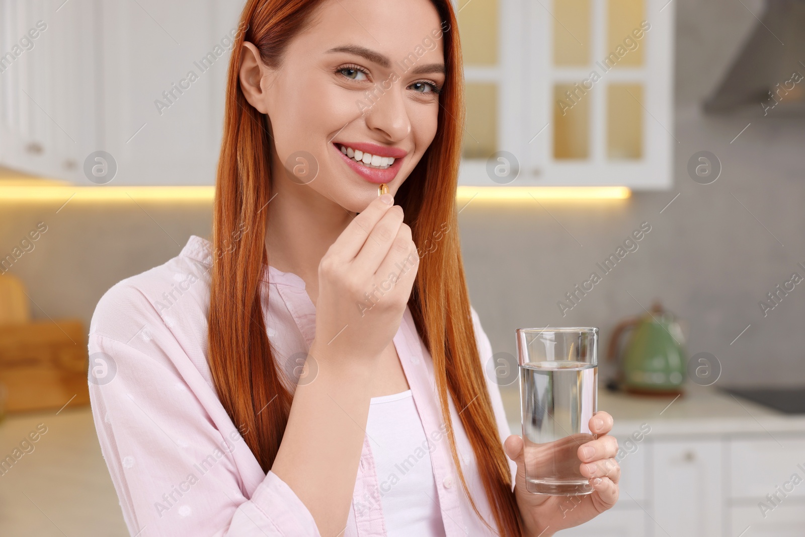 Photo of Beautiful young woman taking vitamin pill at home