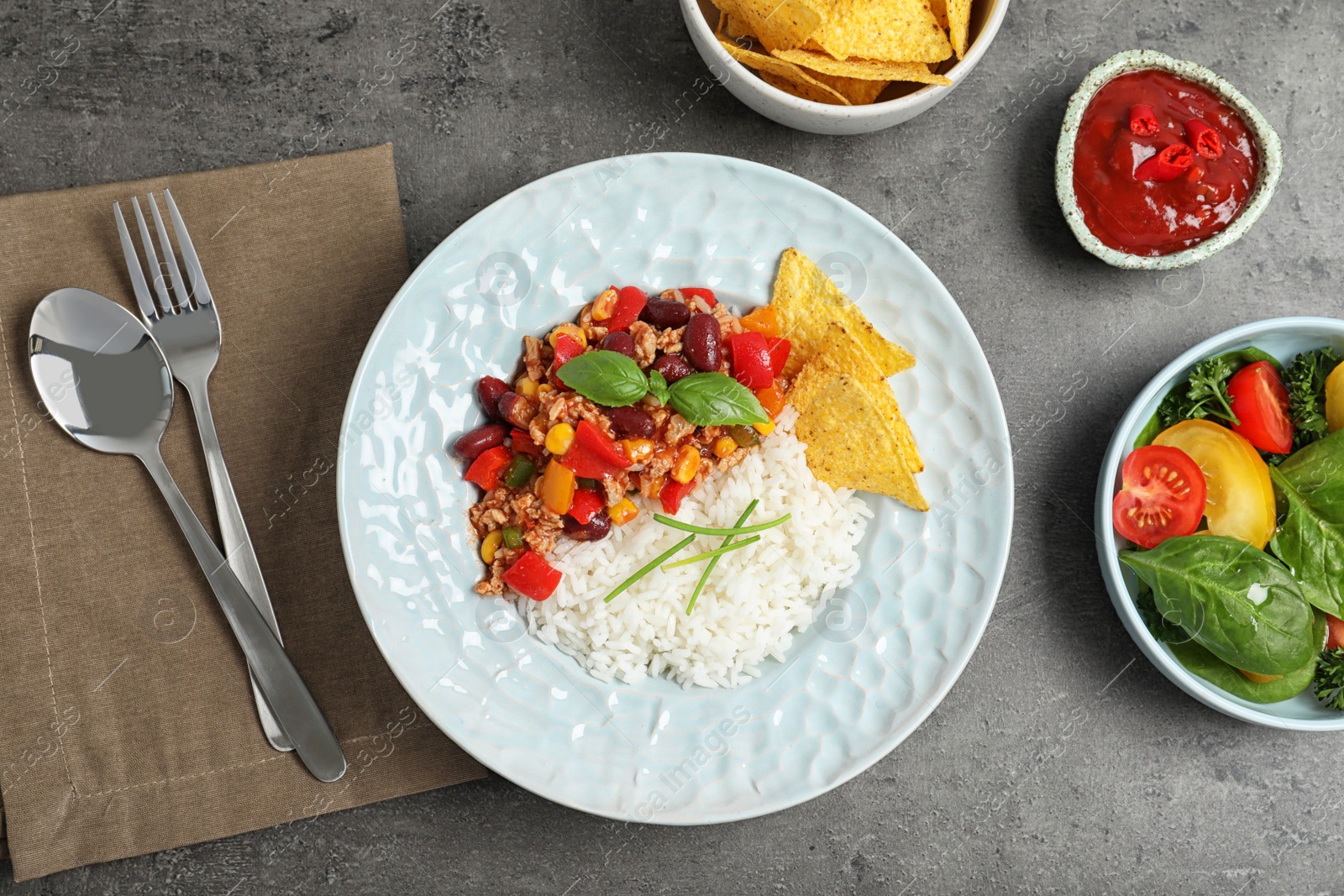 Photo of Tasty chili con carne served with rice on gray table, flat lay