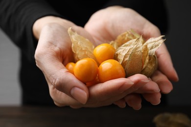Photo of Woman holding pile of ripe physalis fruits and calyxes, closeup
