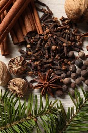 Photo of Different spices and fir branches on wooden table, flat lay