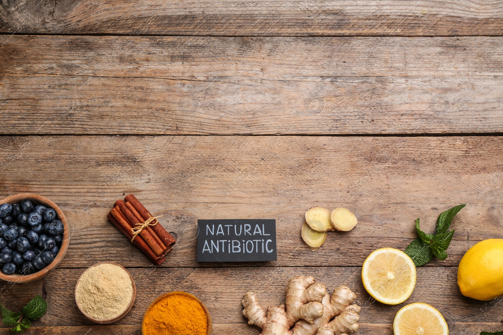 Photo of Different fresh products and card with phrase Natural Antibiotic on wooden table, flat lay. Space for text