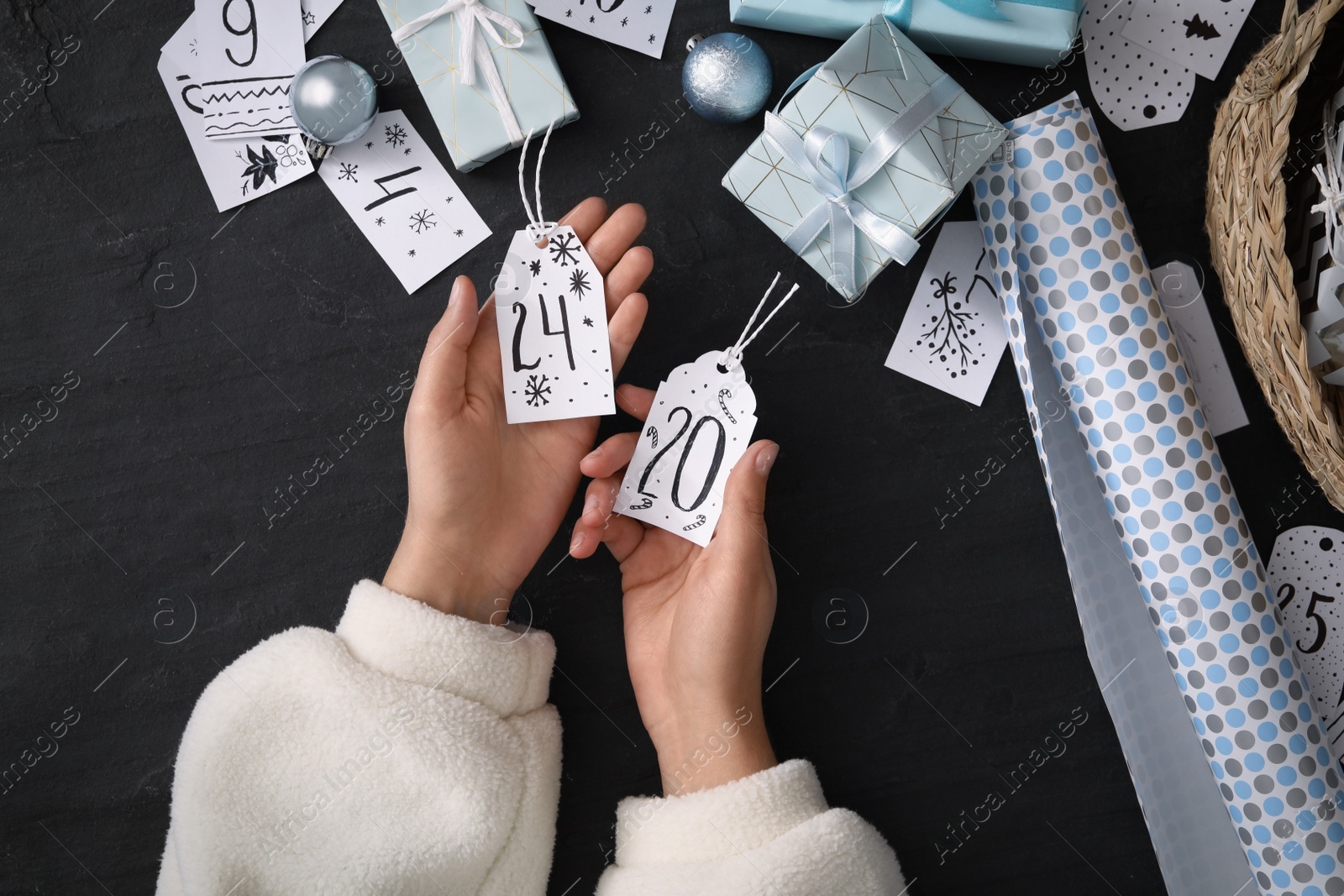 Photo of Woman making advent calendar at black table, top view