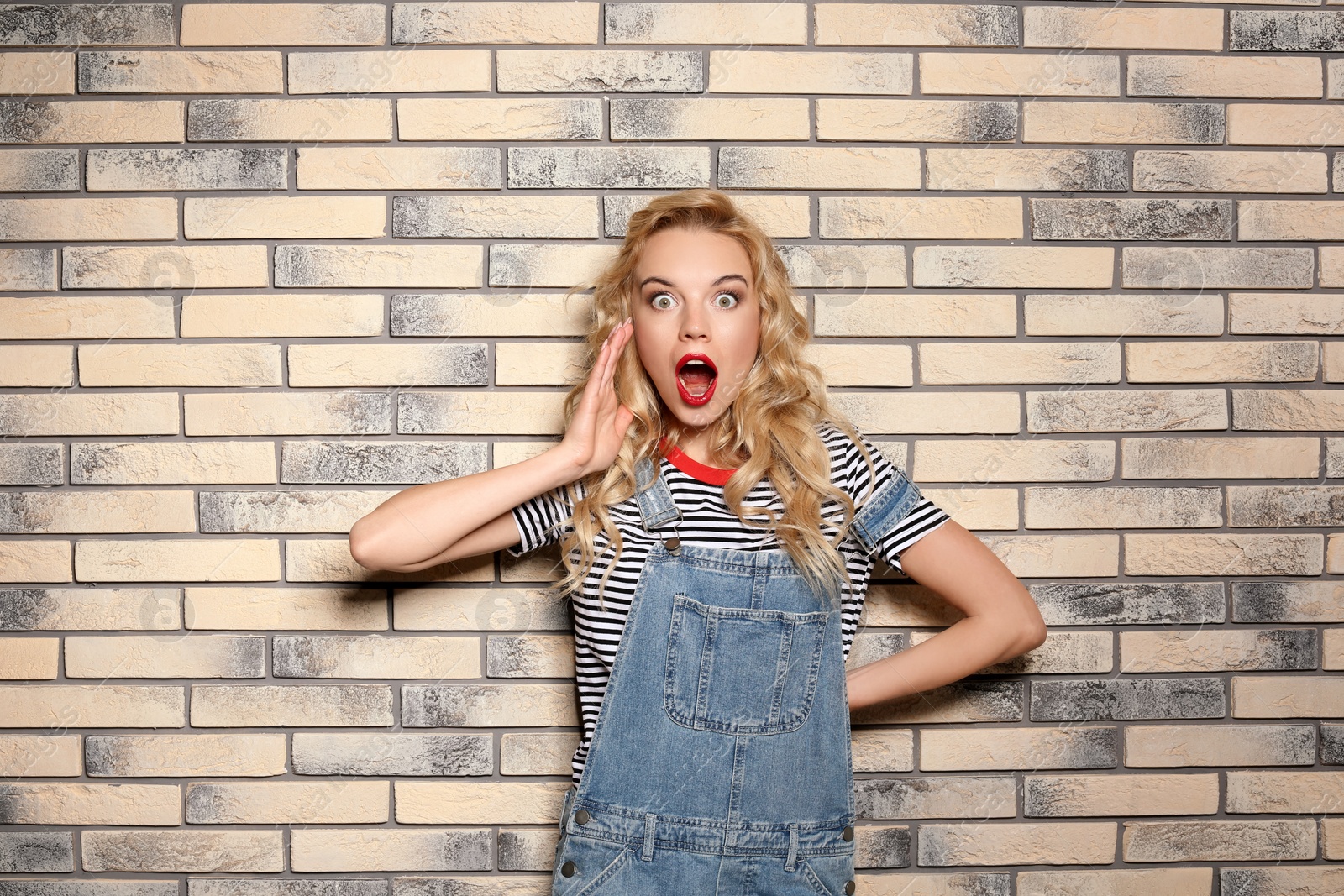 Photo of Emotional stylish young woman on brick wall background