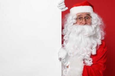 Santa Claus holding blank poster on red background, space for text