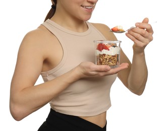 Happy woman eating tasty granola with fresh berries and yogurt on white background, closeup