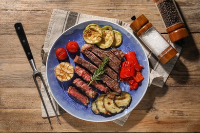 Photo of Delicious grilled beef steak with vegetables and spices on wooden table, flat lay