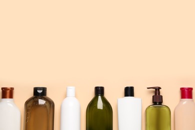 Photo of Different shampoo bottles on beige background, flat lay. Space for text