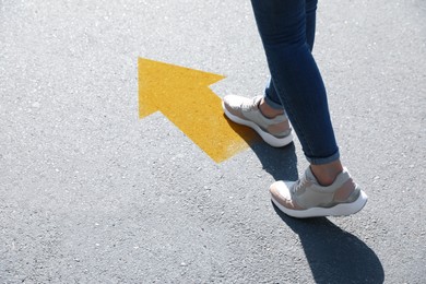 Image of Planning future. Woman walking to drawn mark on road, closeup. Yellow arrow showing direction of way