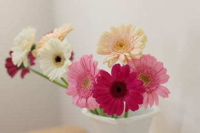 Photo of Vase with beautiful gerbera flowers on blurred background, closeup