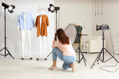 Professional photographer taking picture of ghost mannequins with modern clothes in photo studio