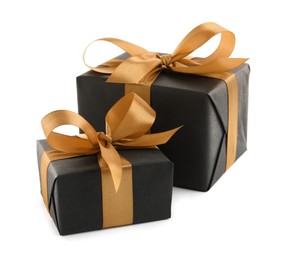 Photo of Black gift boxes with golden bows on white background
