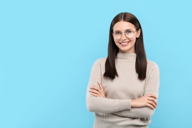 Photo of Portrait of smiling woman in stylish eyeglasses on light blue background. Space for text