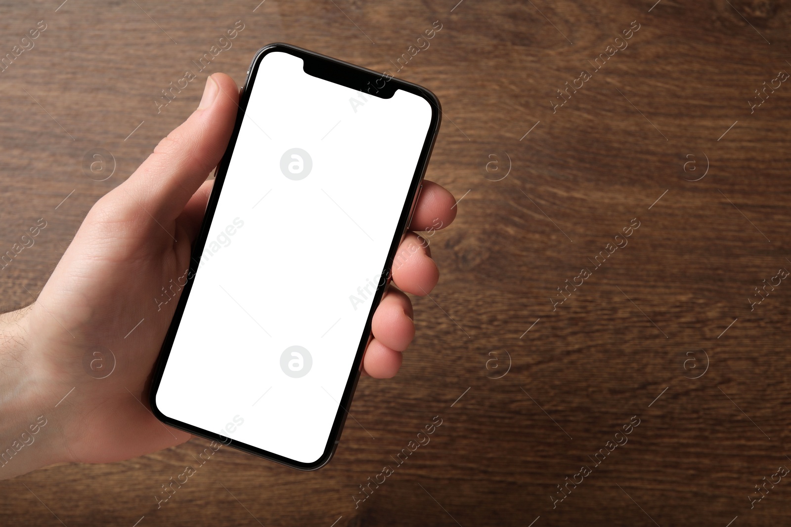 Photo of Woman holding smartphone with blank screen at wooden table, top view. Mockup for design