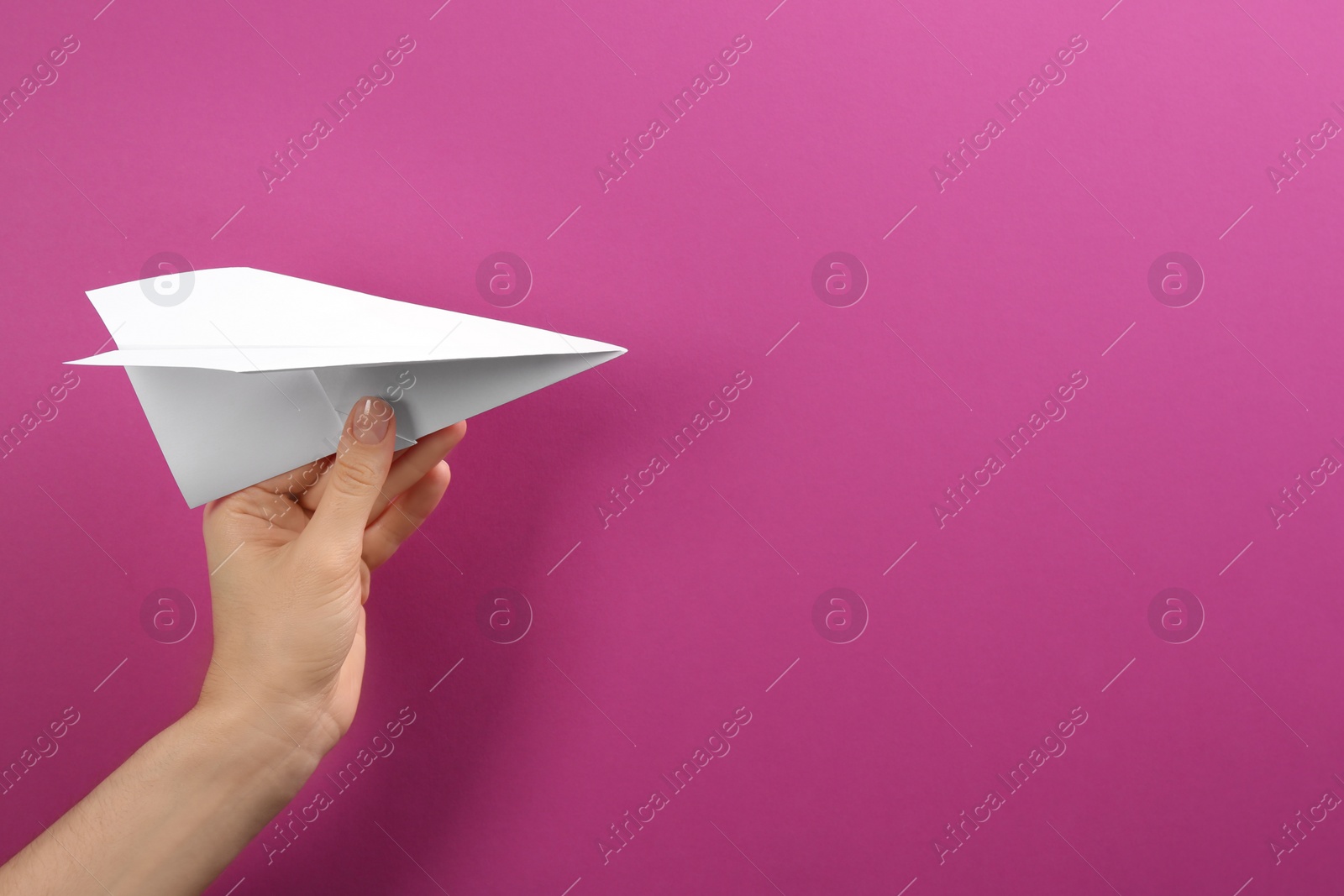 Photo of Woman holding paper plane on purple background, closeup. Space for text