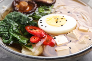 Photo of Delicious vegetarian ramen with egg, mushrooms, tofu and vegetables in bowl, closeup. Noodle soup