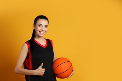 Photo of Basketball player with ball on yellow background. Space for text