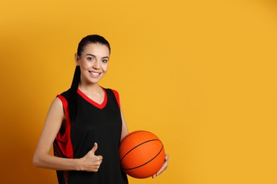 Basketball player with ball on yellow background. Space for text