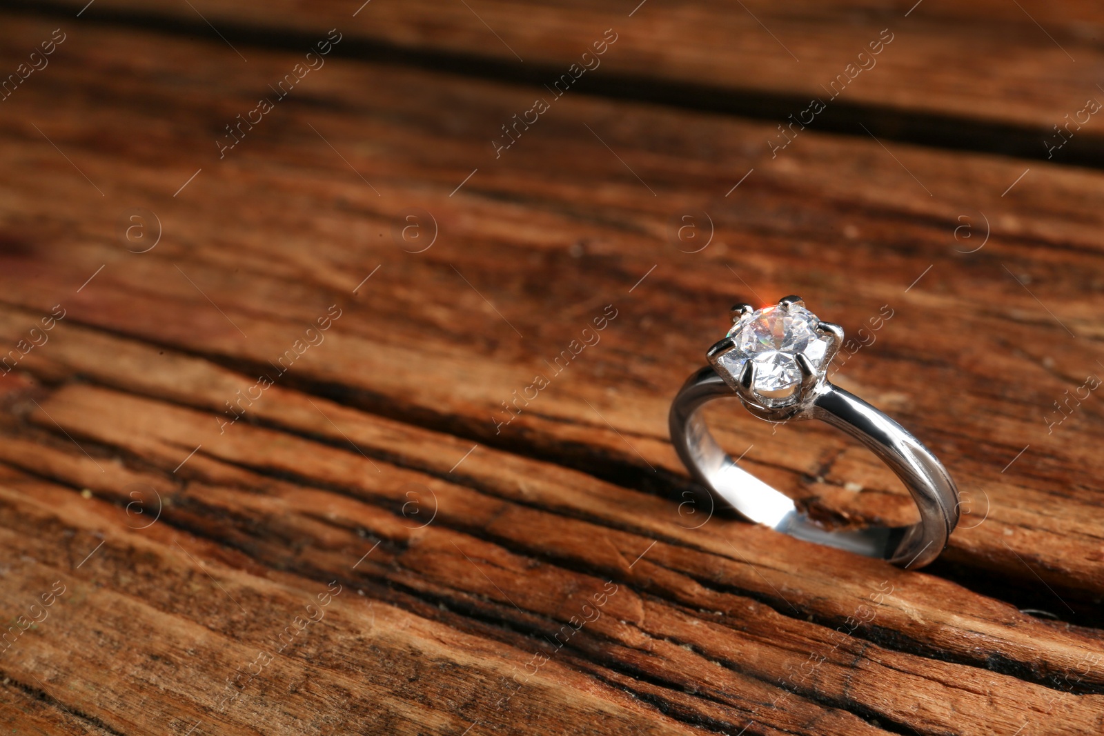 Photo of Beautiful luxury engagement ring with gemstone on wooden background, closeup. Space for text