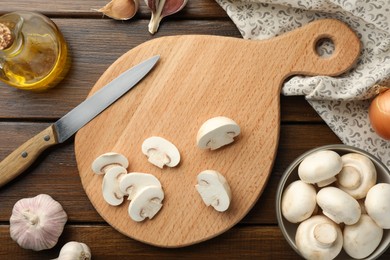 Photo of Cutting board with mushrooms and knife on wooden table, flat lay