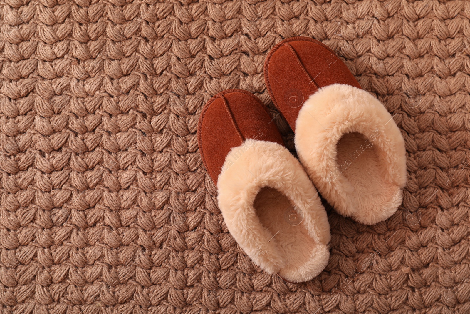 Photo of Brown warm slippers on carpet, flat lay. Space for text