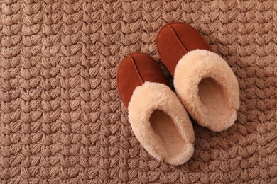 Brown warm slippers on carpet, flat lay. Space for text