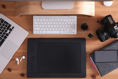 Modern retoucher's workplace with digital devices on wooden table, flat lay