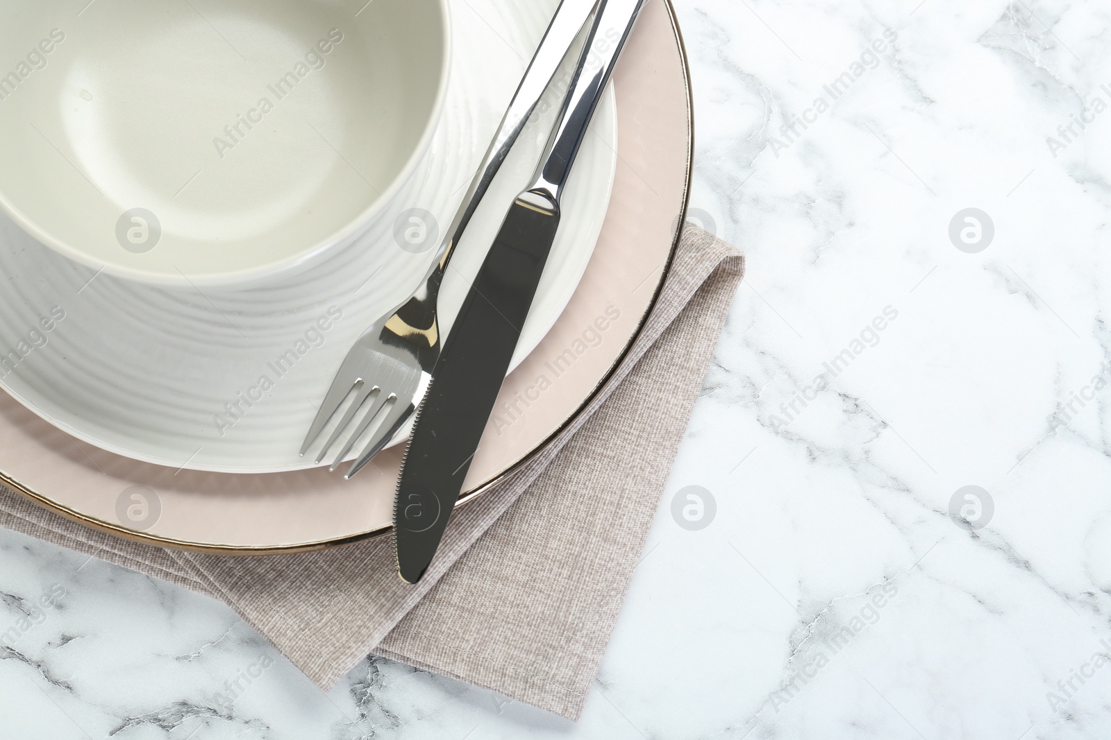 Photo of Clean plates, bowl, cutlery and napkin on white marble table, top view. Space for text