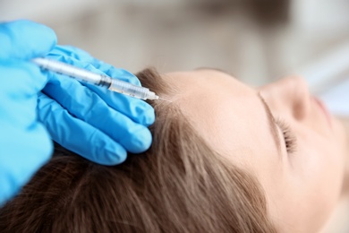 Photo of Young woman with hair loss problem receiving injection in clinic