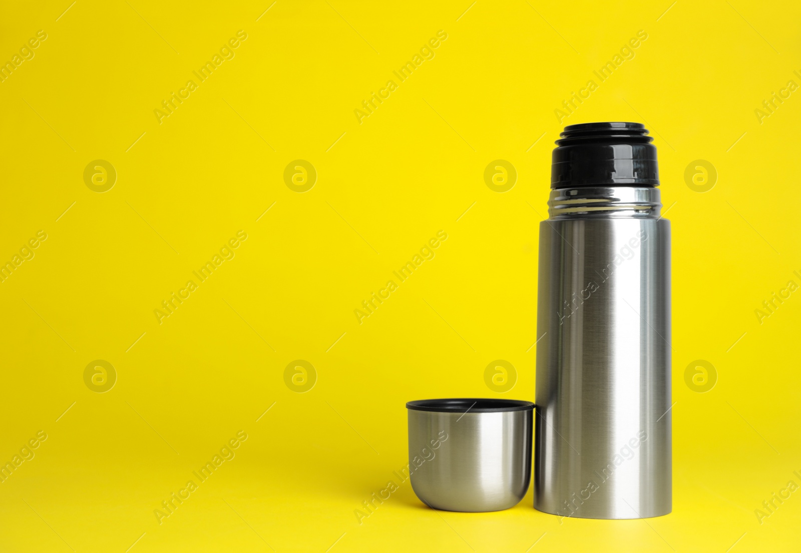 Photo of Stylish thermo bottle on yellow background, space for text