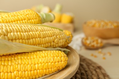Photo of Tasty fresh corn cobs on wooden plate, closeup