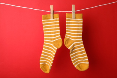 Cute child socks on laundry line against color background