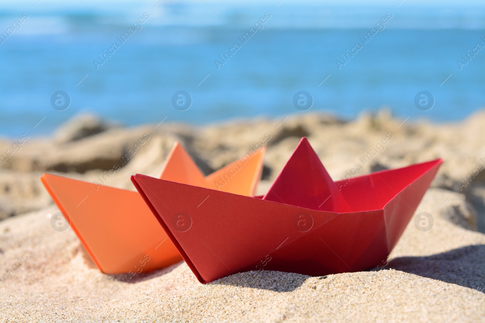 Photo of Two paper boats near sea on sunny day, closeup