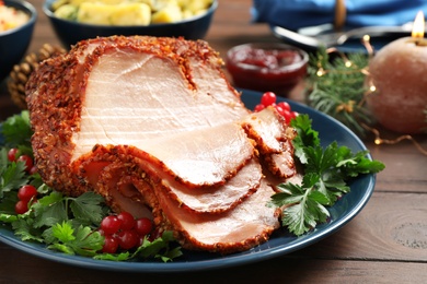 Delicious Christmas ham served with garnish on wooden table, closeup