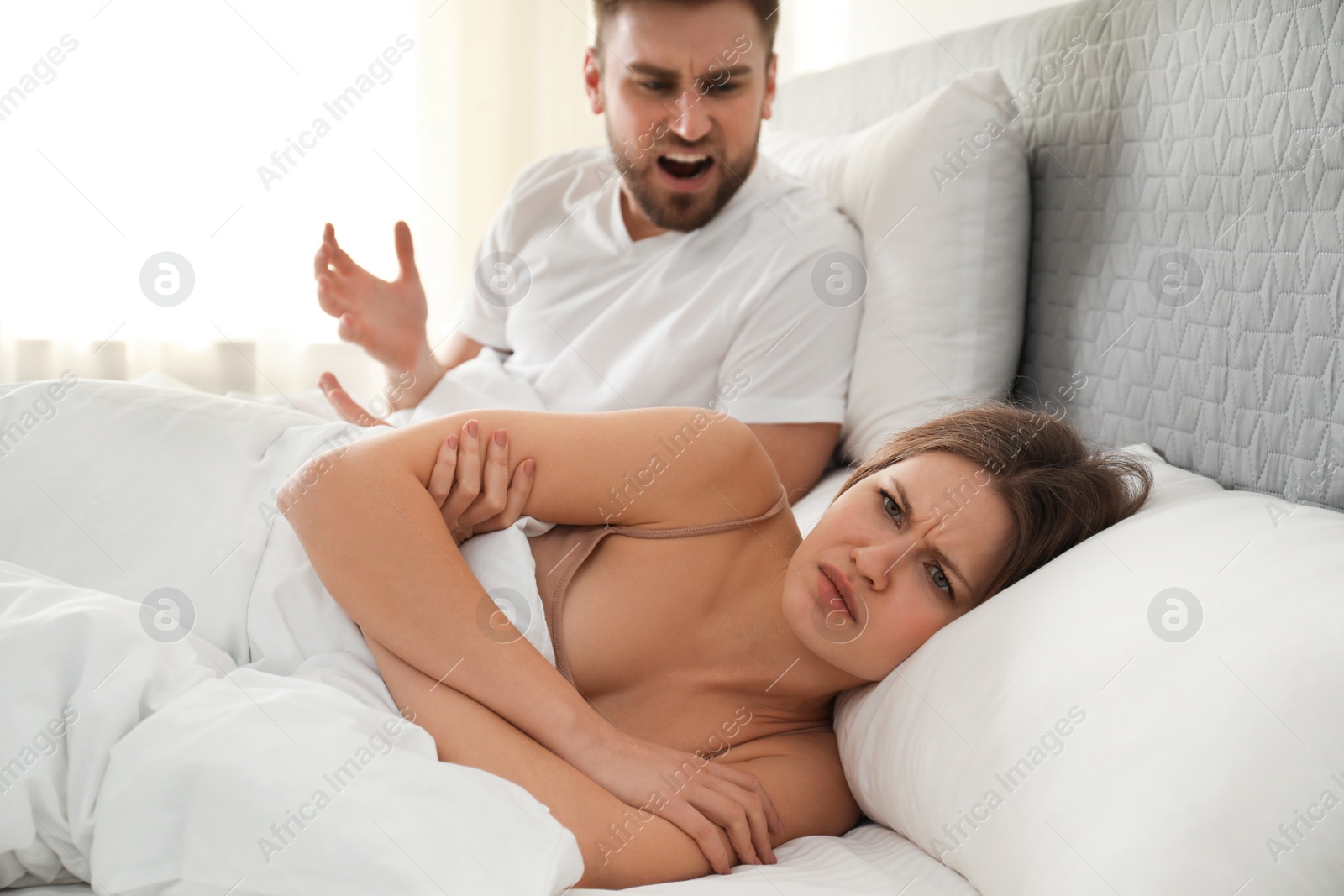 Photo of Young couple quarreling in bed at home. Relationship problems