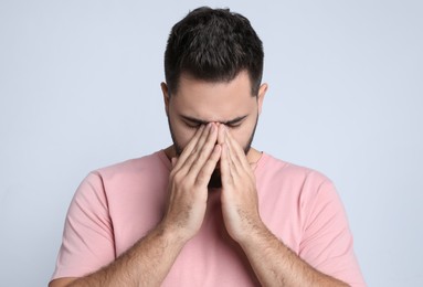 Photo of Young man suffering from headache on light background