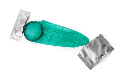 Unrolled condom and torn package on white background, top view. Safe sex