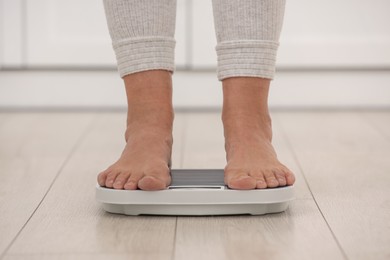 Photo of Menopause, weight gain. Woman standing on floor scales indoors, closeup