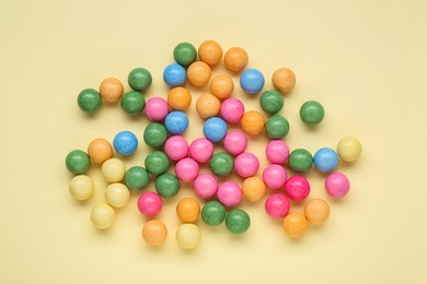 Photo of Many bright chewy gumballs on beige background, flat lay