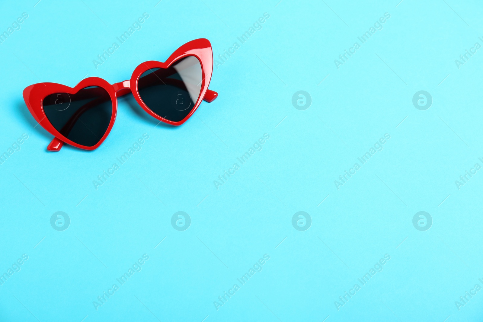 Photo of Red heart shaped sunglasses on color background, top view. Space for text