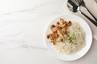 Delicious rice with parsley and mushrooms served on white marble table, flat lay. Space for text