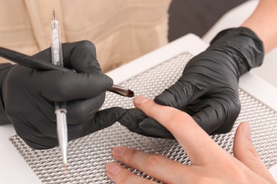 Photo of Professional manicurist working with client, closeup view