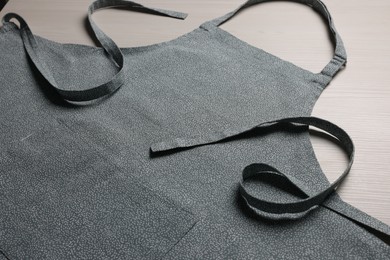 Photo of Stylish apron on white wooden table, closeup. Mockup for design