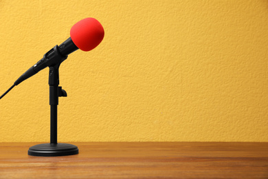 Photo of Modern microphone on wooden table, space for text. Journalist's equipment
