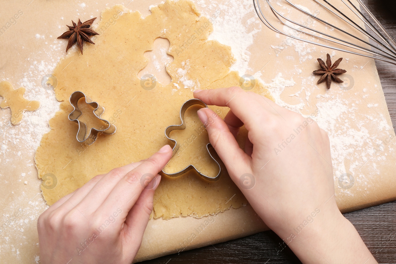 Photo of Woman making Christmas cookies with cutters at wooden table, top view