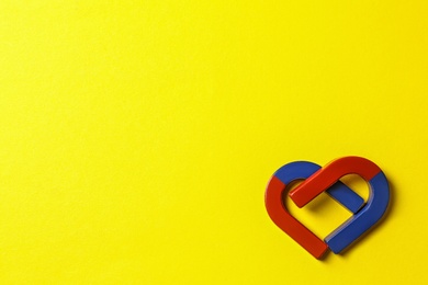 Red and blue horseshoe magnets on yellow background, flat lay. Space for text